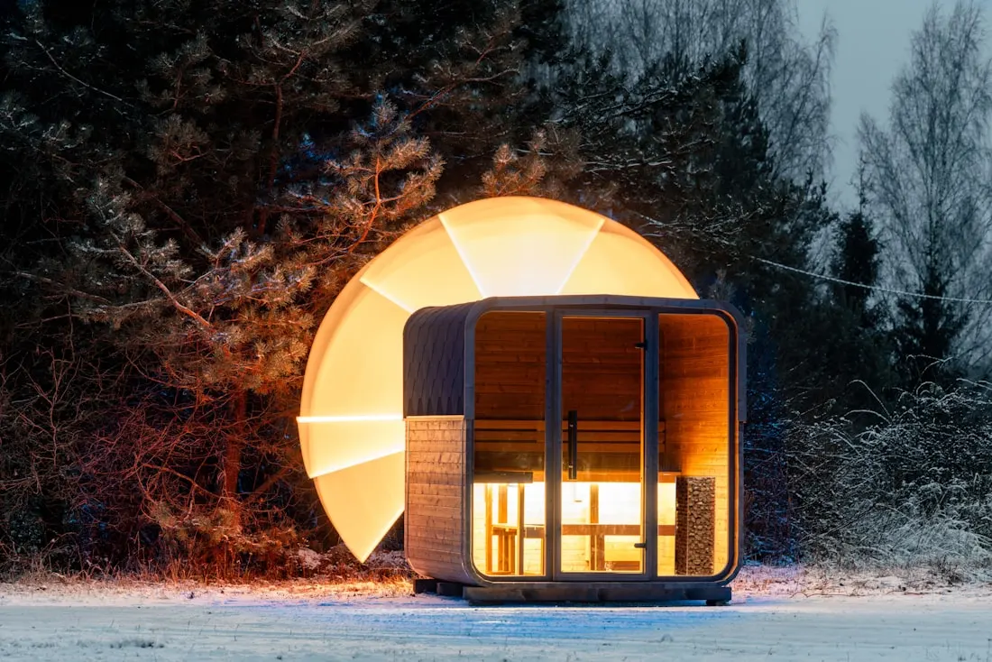 Modern pod sauna with warm light at dusk
